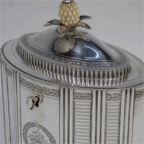 A very handsome Antique Georgian Sterling Silver tea caddy box, having an oval straight-sided body with hand-engraved panels between hand-chased vertical bands of fluting, with hand-engraved laurel-leaf cartouches on either side, a fluted and domed lid with flat invisible hinge and pineapple finial, all sitting on a flat base and with its original lock and key. Made by Henry Chawner of London in 1795. The dimensions of this fine hand-made antique silver tea caddy box are height 16 cms (6.25 inches), length 14 cms (5.5 inches), width 9.5 cms (3.75 inches), and it weighs approx. 333g (10.7 troy ounces).   