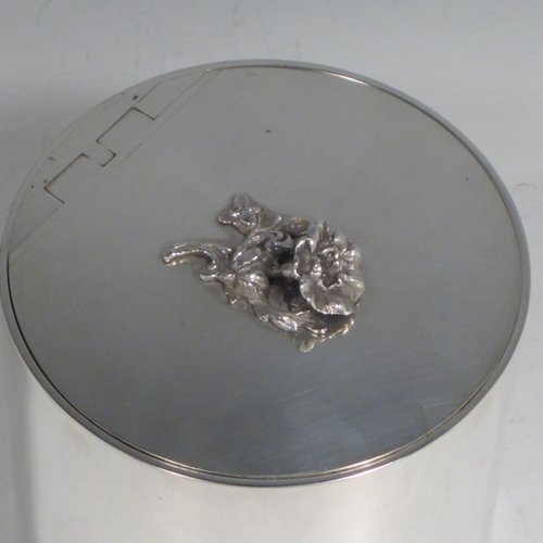 Sterling silver tea caddy box in a Georgian style, having a plain cylindrical body with straight sides, an invisibly hinged flat lid with floral finial, and sitting on a flat base. Made by Alston & Halom of London in 1918. The dimensions of this fine hand-made silver tea caddy box are height 10 cms (4 inches), diameter 11 cms (4.25 inches), and it weighs approx. 437g (14 troy ounces).