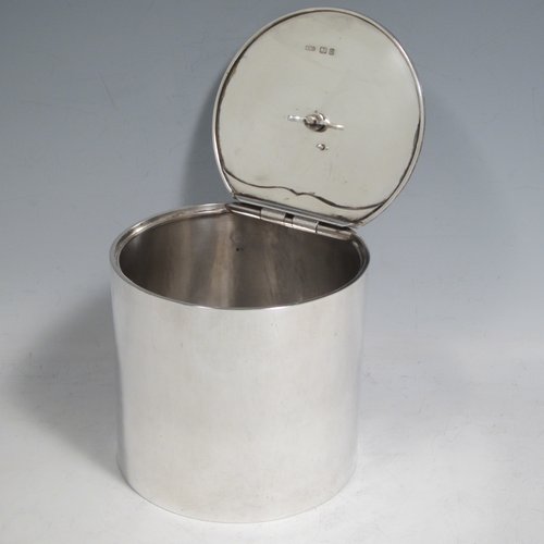 Sterling silver tea caddy box in a Georgian style, having a plain cylindrical body with straight sides, an invisibly hinged flat lid with floral finial, and sitting on a flat base. Made by Alston & Halom of London in 1918. The dimensions of this fine hand-made silver tea caddy box are height 10 cms (4 inches), diameter 11 cms (4.25 inches), and it weighs approx. 437g (14 troy ounces).