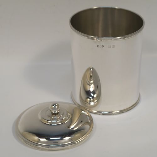 A very handsome Antique Sterling Silver tea caddy box, having a plain cylindrical body with straight sides and applied bead, ribbon and reed top and bottom borders, a slightly domed lift-off lid with a ball finial, and sitting on a flat base. This elegant silver tea caddy box was made by Hukin and Heath of Birmingham in 1924. The dimensions of this fine hand-made antique silver tea caddy box are height 13 cms ( 5inches), diameter 9 cms (3.5 inches), and it weighs approx. 255g (8.2 troy ounces).
