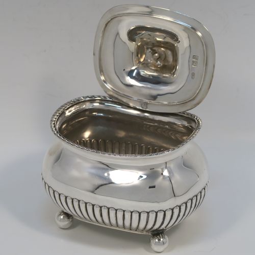 An elegant Antique Edwardian Sterling Silver tea caddy box, having a rectangular bellied body with hand-chased half-fluted decoration, an applied gadroon top border, a hinged domed lid with a black stained wooden finial, and all sitting on four ball feet. This handsome silver tea caddy box was made by Henry Stratford of London in 1902. The dimensions of this fine hand-made antique silver tea caddy box are height 11.5 cms (4.5 inches), length 11.5 cms (4.5 inches), width 9 cms (3.5 inches), and it weighs approx. 230g (7.4 troy ounces).