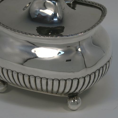 An elegant Antique Edwardian Sterling Silver tea caddy box, having a rectangular bellied body with hand-chased half-fluted decoration, an applied gadroon top border, a hinged domed lid with a black stained wooden finial, and all sitting on four ball feet. This handsome silver tea caddy box was made by Henry Stratford of London in 1902. The dimensions of this fine hand-made antique silver tea caddy box are height 11.5 cms (4.5 inches), length 11.5 cms (4.5 inches), width 9 cms (3.5 inches), and it weighs approx. 230g (7.4 troy ounces).
