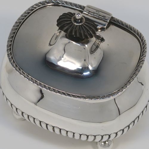 An elegant Antique Edwardian Sterling Silver tea caddy box, having a rectangular bellied body with hand-chased half-fluted decoration, an applied gadroon top border, a hinged domed lid with a black stained wooden finial, and all sitting on four ball feet. This handsome silver tea caddy box was made by Henry Stratford of London in 1902. The dimensions of this fine hand-made antique silver tea caddy box are height 11.5 cms (4.5 inches), length 11.5 cms (4.5 inches), width 9 cms (3.5 inches), and it weighs approx. 230g (7.4 troy ounces).