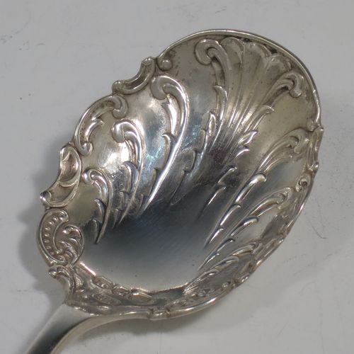 An Antique Sterling Silver tea caddy spoon, with a floral patterned handle, and a hand-chased oval bowl with scroll decoration. Made by Joseph Gloster of Birmingham in 1911. The dimensions of this fine hand-made antique silver tea caddy spoon are length 10 cms (4 inches), width across bowl 3.5 cms (1.3 inches), and it weighs approx. 18g (0.6 troy ounces).