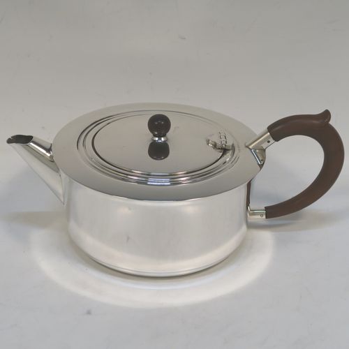 A very handsome and stylish Sterling Silver Art Deco style four-piece tea and coffee service, having very plain round bodies, with brown stained wooden handles and finials, and all sitting on flat stepped bases. This very elegant silver tea and coffee service was made by Alvic Products Ltd., of Birmingham in 1947. The dimensions of this fine hand-made Art Deco style tea and coffee set are length of teapot 23 cms (9 inches), height of coffee pot 15 cms (6 inches), and the total weight is approx. 1,127g (36 troy ounces).
