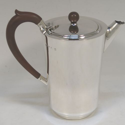 A very handsome and stylish Sterling Silver Art Deco style four-piece tea and coffee service, having very plain round bodies, with brown stained wooden handles and finials, and all sitting on flat stepped bases. This very elegant silver tea and coffee service was made by Alvic Products Ltd., of Birmingham in 1947. The dimensions of this fine hand-made Art Deco style tea and coffee set are length of teapot 23 cms (9 inches), height of coffee pot 15 cms (6 inches), and the total weight is approx. 1,127g (36 troy ounces).