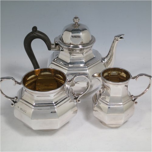 An Antique Victorian Sterling Silver three-piece bachelor tea set, having hexagonal panelled bodies, the teapot with a domed hinged lid with cast finial, a black wooden scroll handle, the cream and sugar bowl with gold gilt interiors and scroll handles, and all sitting on collet feet. Made by Joshua Vander of London in 1889. The dimensions of this fine hand-made antique silver tea set are height of teapot 14 cms (5.5 inches), length of teapot 17.5 cms (7 inches), with a total weight of approx. 589g (19 troy ounces).   