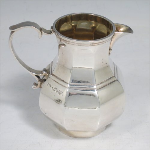 An Antique Victorian Sterling Silver three-piece bachelor tea set, having hexagonal panelled bodies, the teapot with a domed hinged lid with cast finial, a black wooden scroll handle, the cream and sugar bowl with gold gilt interiors and scroll handles, and all sitting on collet feet. Made by Joshua Vander of London in 1889. The dimensions of this fine hand-made antique silver tea set are height of teapot 14 cms (5.5 inches), length of teapot 17.5 cms (7 inches), with a total weight of approx. 589g (19 troy ounces).