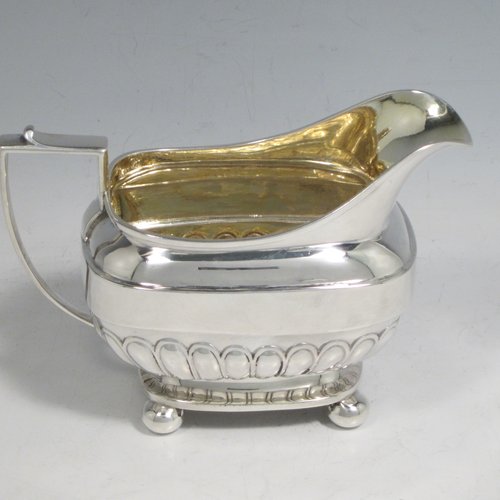 Antique Georgian sterling silver three-piece Regency style tea set, having a teapot, sugar bowl and cream jug. The bodies all hand-chased with half-fluted decoration, the sugar and creamer with gold-gilt interiors, the teapot with silver handle and finial, and an invisibly hinged lid, and all sitting on four ball feet. Made by Rebecca Emes and Edward Barnard of London in 1811 and 1813. The dimensions of this fine hand-made silver tea service are length of teapot 27 cms (10.5 inches), height 16 cms (6.3 inches), and it weighs a total of approx. 1,262g (41 troy ounces).    