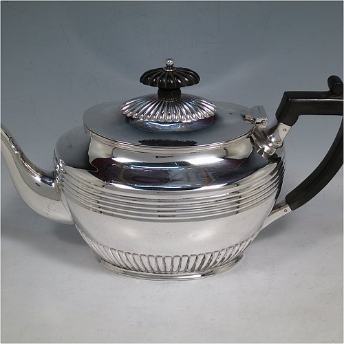 An elegant Antique Victorian Sterling Silver three-piece tea set, having oval shaped bodies, with fine half-fluted and reeded hand-chased decoration, reeded handles on the sugar & cream jug together with gold-gilt interiors, and a wooden handle & finial on the teapot, and all sitting on collet foot bases. This handsome silver tea service was made by Henry Stratford of Sheffield in 1900. The dimensions of this fine hand-made antique silver tea set are length of teapot 28 cms (11 inches), height 15 cms (6 inches), and the total weight is approx. 775g (25 troy ounces).
