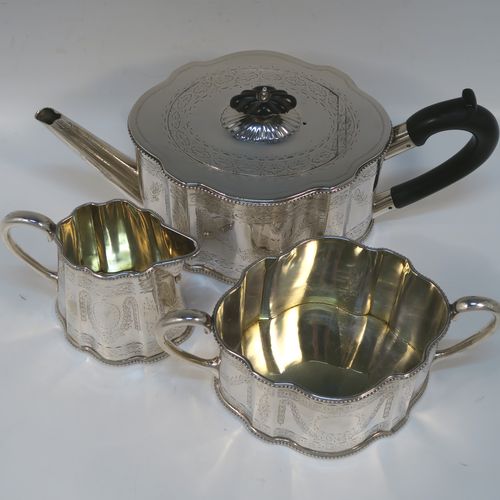 A heavy and very pretty Antique Victorian Sterling Silver three-piece tea set, consisting of a teapot, sugar bowl, and cream jug, having shaped oval bodies with straight sides, applied bead-edged borders, and hand-engraved Neoclassical style decoration, the teapot with a black wooden handle, finial, and a hinged lid with a flat invisible hinge, the sugar and creamer with scroll handles, gold-gilt interiors, and all sitting on flat bases. This beautiful silver three-piece tea set was made by Joseph Angell II and Robert Harper of London in 1872. The dimensions of this fine hand-made silver tea set are height of teapot 13.5 cms (5.3 inches), length 29 cms (11.5 inches), and it weighs a total of approx. 1,240g (44 troy ounces).