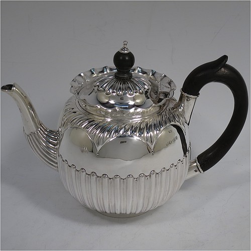 A very pretty Antique Victorian Sterling Silver three-piece bachelor tea set, having round bellied bodies with beautiful bands of hand-chased fluted decoration and wavy top borders, the teapot with a hinged lid and wooden finial, a wooden scroll handle, and the cream and sugar bowl with gold-gilt interiors, all sitting on collet feet. Made by Thomas Hayes of Birmingham in 1888. The dimensions of this fine hand-made antique silver bachelor tea set are height of teapot 14 cms (5.5 inches), length of teapot 19 cms (7.5 inches), with a total weight of approx. 474g (15.3 troy ounces).