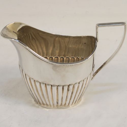 A handsome Antique Sterling Silver Bachelor three-piece tea set, having oval shaped bodies, with half-fluted hand-chased decoration, with reeded handles on the sugar & cream jug, a wooden handle and finial on the teapot, and all sitting on flat bases. This beautiful antique silver bachelor tea set was all made by John Milward Banks of Birmingham in 1896. The dimensions of this fine hand-made antique silver bachelor tea set are length of teapot 21.5 cms (8.5 inches), height 12.5 cms (5 inches), and the total weight is approx. 320g (10.3 troy ounces).