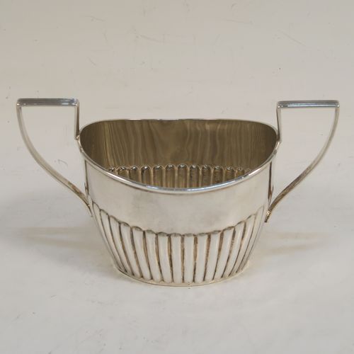 A handsome Antique Sterling Silver Bachelor three-piece tea set, having oval shaped bodies, with half-fluted hand-chased decoration, with reeded handles on the sugar & cream jug, a wooden handle and finial on the teapot, and all sitting on flat bases. This beautiful antique silver bachelor tea set was all made by John Milward Banks of Birmingham in 1896. The dimensions of this fine hand-made antique silver bachelor tea set are length of teapot 21.5 cms (8.5 inches), height 12.5 cms (5 inches), and the total weight is approx. 320g (10.3 troy ounces).