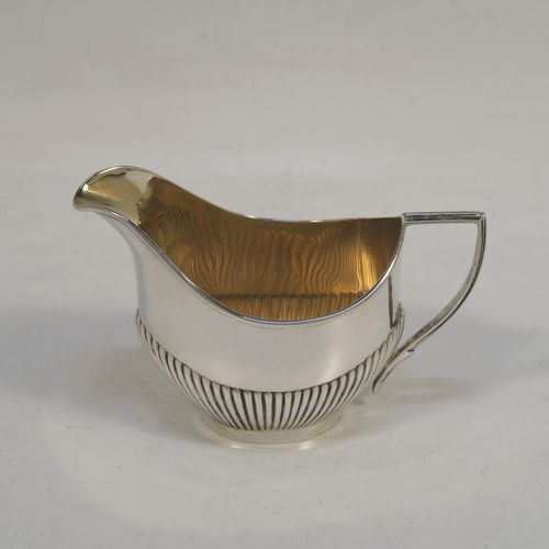A pretty Antique Sterling Silver Bachelor three-piece tea set, having oval shaped bodies, with half-fluted hand-chased decoration, gold-gilt interiors and reeded handles on the sugar & cream jug, a wooden handle and finial on the teapot, and all sitting on flat bases. This beautiful antique silver bachelor tea set was all made by Albert Bloxham of London and Birmingham in 1908 and 1913. The dimensions of this fine hand-made antique silver bachelor tea set are length of teapot 21.5 cms (8.5 inches), height 12 cms (4.75 inches), and the total weight is approx. 300g (9.7 troy ounces).