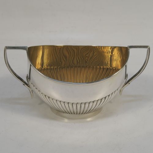 A pretty Antique Sterling Silver Bachelor three-piece tea set, having oval shaped bodies, with half-fluted hand-chased decoration, gold-gilt interiors and reeded handles on the sugar & cream jug, a wooden handle and finial on the teapot, and all sitting on flat bases. This beautiful antique silver bachelor tea set was all made by Albert Bloxham of London and Birmingham in 1908 and 1913. The dimensions of this fine hand-made antique silver bachelor tea set are length of teapot 21.5 cms (8.5 inches), height 12 cms (4.75 inches), and the total weight is approx. 300g (9.7 troy ounces).