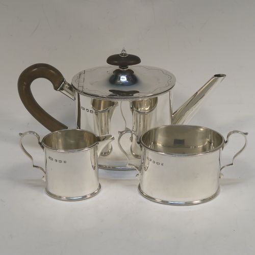 A very pretty Sterling Silver three-piece bachelor sized tea set, consisting of a teapot, sugar bowl, and cream jug, in a plain oval style with straight sides and applied bead-edged borders, the teapot with a brown wooden handle, finial, and a hinged domed lid with a flat invisible hinge, the sugar and creamer with scroll handles, and all sitting on flat bases. This beautiful silver bachelor size three-piece tea set was made by Roberts and Belk of Sheffield in 1940. The dimensions of this fine hand-made silver tea set are height of teapot 11.5 cms (4.5 inches), length 21.5 cms (8.5 inches), and it weighs a total of approx. 450g (14.5 troy ounces).  