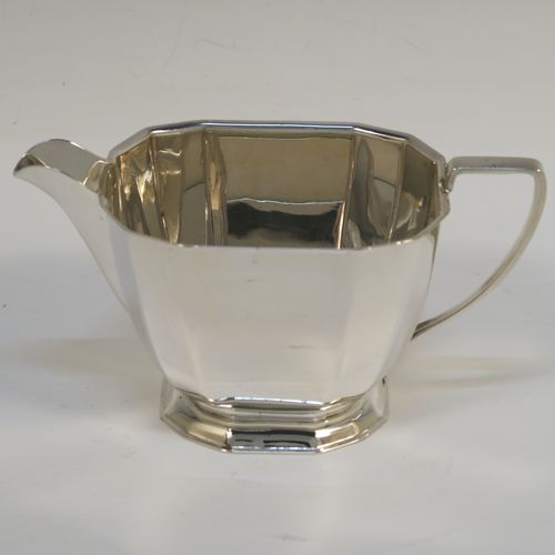 A very handsome Sterling Silver Art Deco style three-piece tea set, consisting of a teapot, sugar bowl, and cream jug, having plain panelled bodies and angular handles, the teapot with a black wooden handle, finial, and a hinged lid, and all sitting on collet feet. This elegant silver tea set was made by the Cooper Brothers of Sheffield in 1966. The dimensions of this fine hand-made Art Deco style silver tea set are height of teapot 13.5 cms (5.3 inches), length 28 cms (11 inches), and it weighs a total of approx. 1,062g (34 troy ounces).