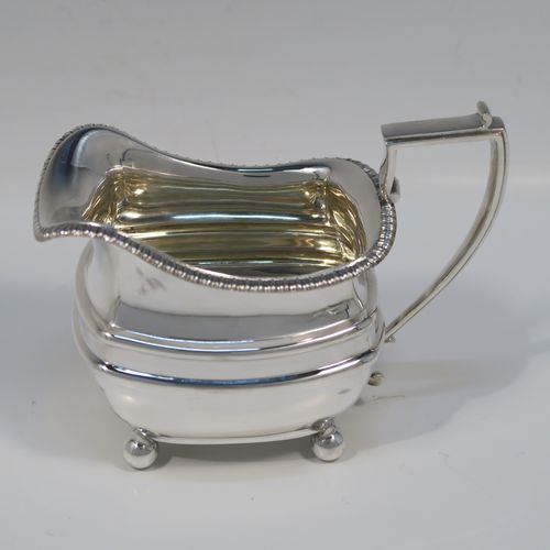 A handsome Antique Edwardian Sterling silver three-piece tea and coffee set, in a Georgian style having plain rectangular bellied bodies and applied gadroon borders, the teapot with invisibly hinged lid, wooden finial and handle, and all sitting on four ball feet. This elegant silver tea set was made by James Dixon and Sons of Sheffield in 1905. The dimensions of this fine hand-made antique silver tea service are length of teapot 29 cms (11.5 inches), height 13.5 cms (5.3 inches), and the total weight is approx. 1,200g (39 troy ounces).