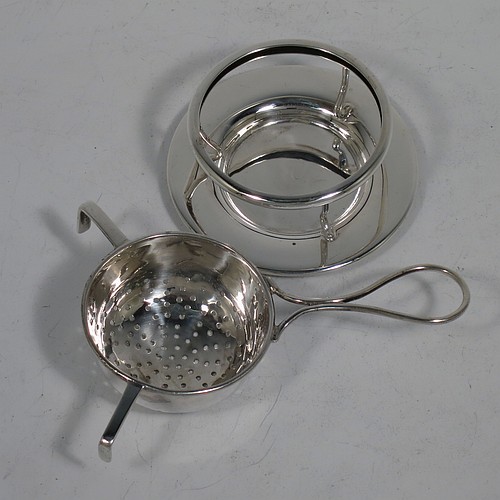 A very stylish Sterling Silver tea strainer and stand, having a round hand-pierced bowl, with wire-work loop handle and two right-angled cup supports, all sitting on an original plain round dregs stand with a wire-work galleried holder on flat base. Made by James Round of Sheffield in 1921. The dimensions of this fine hand-made silver tea strainer and stand are height 4 cms (1.5 inches), length over handle 12 cms (4.75 inches), and it weighs a total of approx. 68g (2.2 troy ounces).