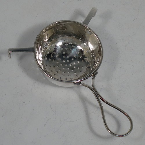 A very stylish Sterling Silver tea strainer and stand, having a round hand-pierced bowl, with wire-work loop handle and two right-angled cup supports, all sitting on an original plain round dregs stand with a wire-work galleried holder on flat base. Made by James Round of Sheffield in 1921. The dimensions of this fine hand-made silver tea strainer and stand are height 4 cms (1.5 inches), length over handle 12 cms (4.75 inches), and it weighs a total of approx. 68g (2.2 troy ounces).