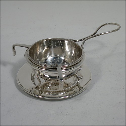 A very stylish Sterling Silver tea strainer and stand, having a round hand-pierced bowl, with wire-work loop handle and two right-angled cup supports, all sitting on an original plain round dregs stand with a wire-work galleried holder on flat base. Made by James Round of Sheffield in 1921. The dimensions of this fine hand-made silver tea strainer and stand are height 4 cms (1.5 inches), length over handle 12 cms (4.75 inches), and it weighs a total of approx. 68g (2.2 troy ounces).