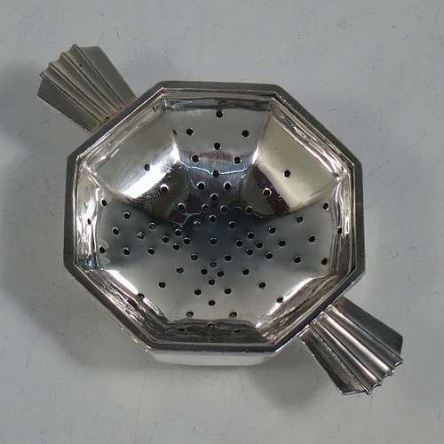 A very handsome Sterling Silver Art Deco style tea strainer and bowl, having an octagonal body with two sun-ray style side-handles, sitting on an original octagonal dregs bowl with a collet foot. Made by Hukin and Heath of Birmingham in 1937. The dimensions of this fine hand-made Art Deco sterling silver tea strainer and bowl are length 11 cms (4.3 inches), depth 6.5 cms (2.5 inches), height 3 cms (1.25 inches), with a total weight approx. 94g (3 troy ounces).