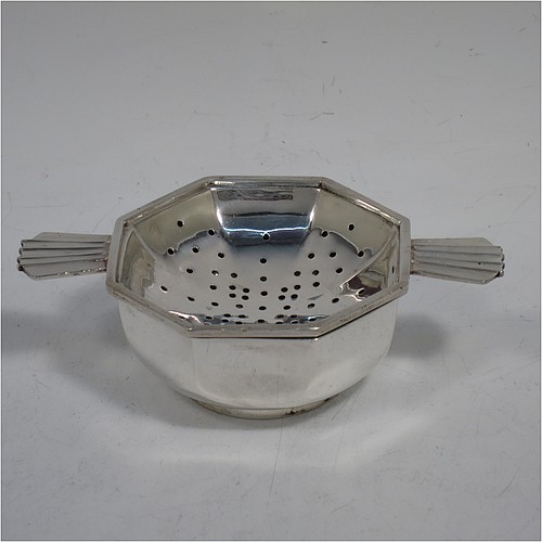 A very handsome Sterling Silver Art Deco style tea strainer and bowl, having an octagonal body with two sun-ray style side-handles, sitting on an original octagonal dregs bowl with a collet foot. Made by Hukin and Heath of Birmingham in 1937. The dimensions of this fine hand-made Art Deco sterling silver tea strainer and bowl are length 11 cms (4.3 inches), depth 6.5 cms (2.5 inches), height 3 cms (1.25 inches), with a total weight approx. 94g (3 troy ounces).