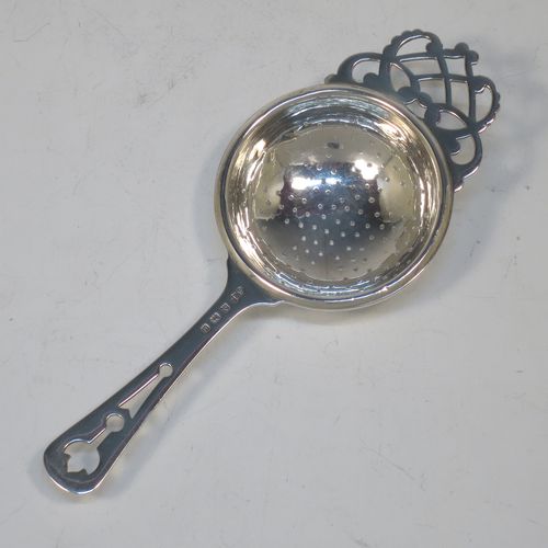 A pretty Sterling Silver tea strainer and bowl, having a hand-pierced handle, a round hand-pierced bowl with hand-cut side holder, and sitting on a plain round dregs stand with a band of piercing and bellied sides. Made by William Suckling Ltd., of Birmingham in 1933. The dimensions of this fine hand-made silver tea strainer & stand are length 14.5 cms (5.75 inches), diameter of stand 6 cms (2.3 inches), with a total weight of approx. 75g (2.4 troy ounces).  