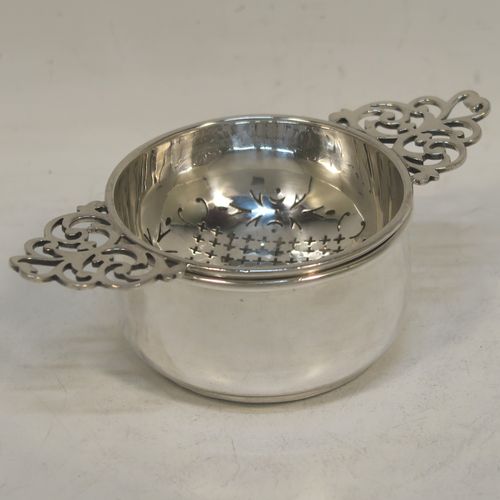 A handsome Sterling Silver tea strainer and dregs bowl in a Georgian lemon strainer style, having a round hand-pierced bowl, with two hand-pierced side-handles, and sitting on an original plain round dregs stand with a flat base. Made by Mappin and Webb of Birmingham in 1930. The dimensions of this fine hand-made silver tea strainer and bowl are height 4 cms (1.5 inches), width across handles 12 cms (4.75 inches), and it weighs a total of approx. 86g (2.8 troy ounces).  