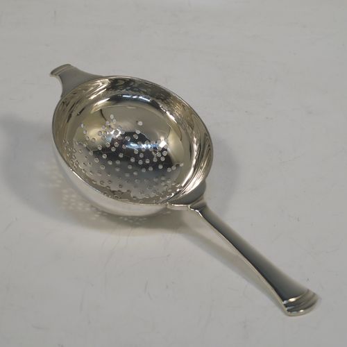 A handsome Art Deco style Sterling Silver tea strainer and bowl, having a round hand-pierced strainer with reeded borders, and sitting on its original plain round bowl on a pedestal foot. This elegant silver tea strainer and bowl was made by Edward Barnard of London in 1955. The dimensions of this fine hand-made silver tea strainer and bowl are length 14 cms (5.5 inches), diameter of bowl 6.5 cms (2.6 inches), and with a total weight of approx. 100g (3.2 troy ounces).