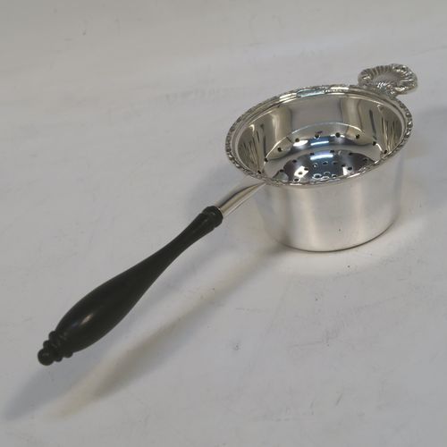 A very pretty Sterling Silver tea strainer and bowl, having a plain black stained wood-turned handle, a round hand-pierced bowl with an applied floral border and a cast shell side holder, and sitting on a plain round dregs bowl with a flat base. This beautiful silver tea strainer and bowl were made by Francis Howard of Sheffield in 1984. The dimensions of this fine hand-made silver tea strainer & bowl are length 18 cms (7 inches), diameter of bowl 6.5 cms (2.5 inches), and with a total weight of approx. 90g (3 troy ounces).  