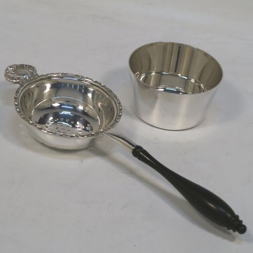 A very pretty Sterling Silver tea strainer and bowl, having a plain black stained wood-turned handle, a round hand-pierced bowl with an applied floral border and a cast shell side holder, and sitting on a plain round dregs bowl with a flat base. This beautiful silver tea strainer and bowl were made by Francis Howard of Sheffield in 1984. The dimensions of this fine hand-made silver tea strainer & bowl are length 18 cms (7 inches), diameter of bowl 6.5 cms (2.5 inches), and with a total weight of approx. 90g (3 troy ounces).  