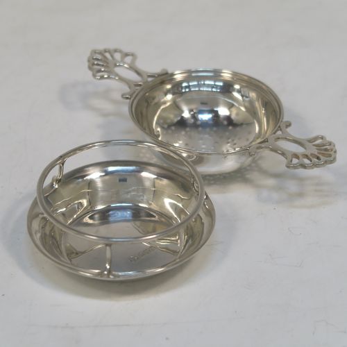 A very stylish Antique Sterling Silver tea strainer and stand, having a round hand-pierced bowl with two pierced side-handles, all sitting on an original plain round dregs stand with a wire-work galleried holder on a flat base. This elegant antique silver tea strainer and stand was made by Thomas Bradbury and Sons of Sheffield in 1918 / 1919. The dimensions of this fine hand-made antique silver tea strainer and stand are height 3 cms (1.25 inches), length over handles 11.5 cms (4.5 inches), and it weighs a total of approx. 44g (1.4 troy ounces).