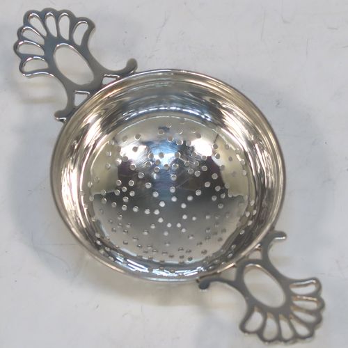 A very stylish Antique Sterling Silver tea strainer and stand, having a round hand-pierced bowl with two pierced side-handles, all sitting on an original plain round dregs stand with a wire-work galleried holder on a flat base. This elegant antique silver tea strainer and stand was made by Thomas Bradbury and Sons of Sheffield in 1918 / 1919. The dimensions of this fine hand-made antique silver tea strainer and stand are height 3 cms (1.25 inches), length over handles 11.5 cms (4.5 inches), and it weighs a total of approx. 44g (1.4 troy ounces).
