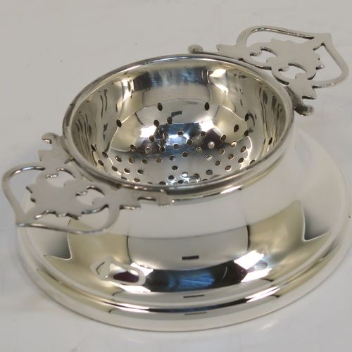 A handsome Sterling Silver tea strainer and dregs bowl, having a round hand-pierced bowl, with two hand-pierced side-handles, and sitting on an original plain round dregs stand. This elegant silver tea strainer and bowl was made by Larson Ltd. of Birmingham in 1957. The dimensions of this fine hand-made silver tea strainer and dregs stand are height 3 cms (1.25 inches), diameter of dregs stand 8 cms (3.25 inches), and it weighs a total of approx. 63g (2 troy ounces).   