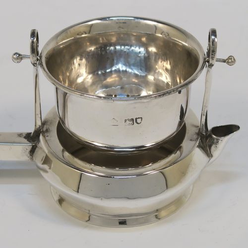 A very unusual Antique Edwardian Sterling Silver gimble-mounted tea strainer on a teapot style stand, having a round hand-pierced bowl mounted on two side stands, all sitting on an original plain round dregs stand in the shape of a teapot, together with an original wooden insulated side-handle. This rare antique silver tea strainer and stand was made by Fredericks Ltd., of London in 1907. The dimensions of this fine hand-made antique silver tea strainer and stand are height 5.5 cms (2.25 inches), length including handle 17 cms (6.75 inches), and it weighs a total of approx. 50g (1.6 troy ounces).   
