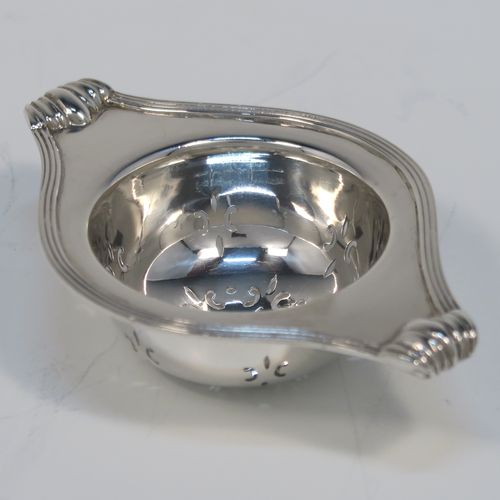 A very stylish Antique Sterling Silver tea strainer and stand, having a round hand-pierced bowl with an applied reeded border and side-handles, all sitting on an original plain round dregs stand with a wire-work galleried holder  with three cabriolet legs. This elegant silver tea strainer and stand was made by Robert Pringle of London in 1928. The dimensions of this fine hand-made silver tea strainer and stand are height 4 cms (1.5 inches), length over handles 10 cms (4 inches), and it weighs a total of approx. 77g (2.5 troy ounces).   