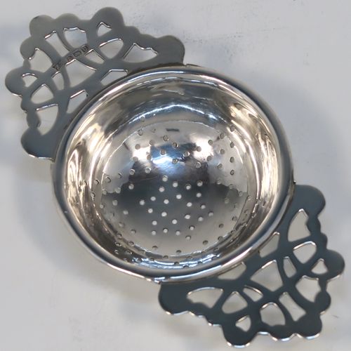 A handsome Sterling Silver tea strainer and dregs bowl, having a Georgian lemon strainer style round hand-pierced bowl, with two hand-pierced side-handles, and sitting on an original plain round dregs stand with a square base. This elegant silver tea strainer and bowl was made by Thomas Bishton of Birmingham in 1944. The dimensions of this fine hand-made silver tea strainer and dregs stand are height 2.5 cms (1 inch), length of strainer 11.5 cms (4.25 inches), and the dregs stand is 7.5 cms (3 inches) square inches), and it weighs a total of approx. 68g (2.2 troy ounces).