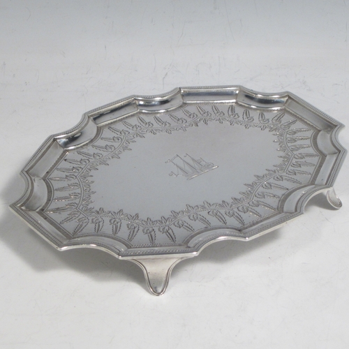Antique Georgian sterling silver Neoclassical style teapot stand having a shaped rectangular body with a raised border, a hand-engraved ground with floral decoration, and sitting on four flange feet. Made by Henry Chawner of London in 1789. The dimensions of this fine hand-made silver teapot stand are length 16.5 cms (6.5 inches), width 12.5 cms (5 inches), and it weighs approx. 140g (4.5 troy ounces). Please note that this item is crested.
	   
