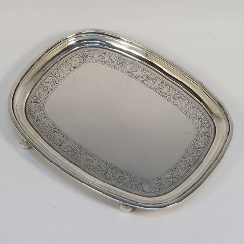 A very pretty Antique Georgian Sterling Silver teapot stand, having a rectangular body with rounded corners and a band of bright-cut hand-engraved floral decoration, a raised border with an applied reeded edge, and sitting on four ball feet. This elegant antique silver teapot stand was made by Soloman Hougham of London in 1804. The dimensions of this fine hand-made antique silver teapot stand are length 16 cms (6.3 inches), width 12.5 cms (5 inches), and it weighs approx. 153g (4.9 troy ounces).