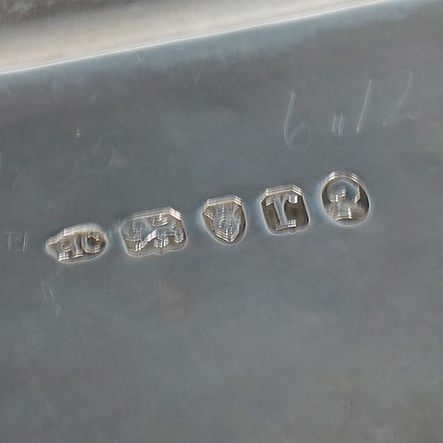 An Antique Georgian Sterling Silver Neoclassical style teapot stand having a lobed rectangular body with a raised edge and applied reeded border, a hand-engraved ground with floral bands of decoration and a central cartouche with laurel-leaf surround, and all sitting on four flange feet. Made by Henry Chawner of London in 1792. The dimensions of this fine hand-made antique silver teapot stand are length 20 cms (8 inches), width 13 cms (5.25 inches), and it weighs approx. 191g (6 troy ounces). Please note that this item is crested.
