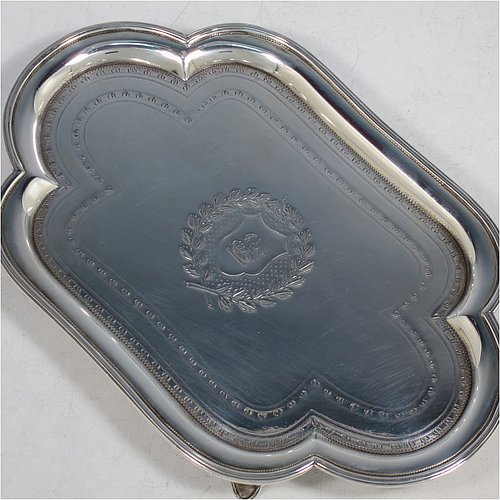 An Antique Georgian Sterling Silver Neoclassical style teapot stand having a lobed rectangular body with a raised edge and applied reeded border, a hand-engraved ground with floral bands of decoration and a central cartouche with laurel-leaf surround, and all sitting on four flange feet. Made by Henry Chawner of London in 1792. The dimensions of this fine hand-made antique silver teapot stand are length 20 cms (8 inches), width 13 cms (5.25 inches), and it weighs approx. 191g (6 troy ounces). Please note that this item is crested.