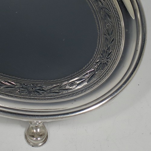 A very handsome Antique Edwardian Sterling Silver teapot stand, having an oval body with a band of hand-engraved floral decoration, a raised border with an applied reeded edge, and sitting on four cast hoof feet. Made by the Pairpoint Brothers of London in 1905. The dimensions of this fine hand-made antique silver teapot stand are length 17.5 cms (7 inches), width 13 cms (5 inches), and it weighs approx. 238g (7.8 troy ounces).