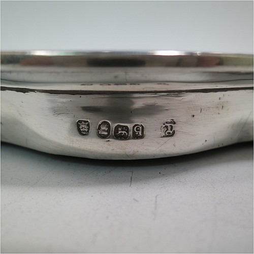 A very handsome Antique Georgian Sterling Silver teapot stand, having a shaped and cut-cornered oval body with an applied and engraved border, the flat ground with a hand-engraved band of stipple-work, and all sitting on a flat wooden base with green felt cover. Made by John Denziloe of London in 1791. The dimensions of this fine hand-made antique silver teapot stand are length 17 cms (6.75 inches), and width 13 cms (5 inches). Please note that this item is crested.