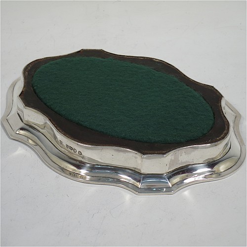 A very handsome Antique Georgian Sterling Silver teapot stand, having a shaped and cut-cornered oval body with an applied and engraved border, the flat ground with a hand-engraved band of stipple-work, and all sitting on a flat wooden base with green felt cover. Made by John Denziloe of London in 1791. The dimensions of this fine hand-made antique silver teapot stand are length 17 cms (6.75 inches), and width 13 cms (5 inches). Please note that this item is crested.