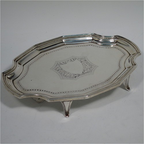 An Antique Victorian Scottish Sterling Silver teapot stand, having a shaped and cut-cornered oval body with an applied reeded border, the flat ground with a hand-engraved beaded band surrounding a central vacant cartouche, and all sitting on four flange feet. Made by Hamilton & Inches of Edinburgh in 1883. The dimensions of this fine hand-made antique silver teapot stand are length 18 cms (7 inches), width 13 cms (5 inches), and it weighs approx. 150g (4.8 troy ounces).   