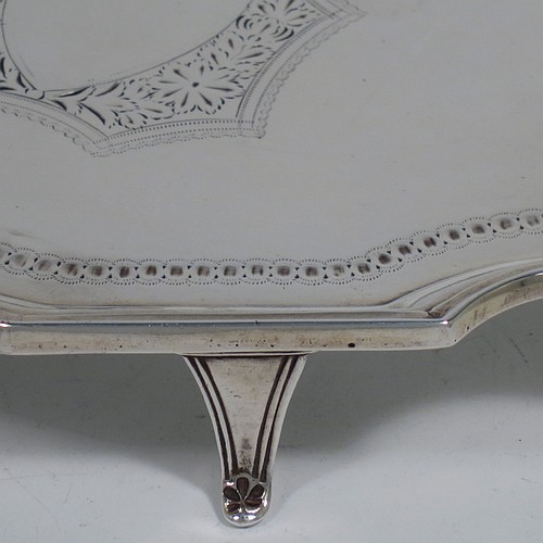 An Antique Victorian Scottish Sterling Silver teapot stand, having a shaped and cut-cornered oval body with an applied reeded border, the flat ground with a hand-engraved beaded band surrounding a central vacant cartouche, and all sitting on four flange feet. Made by Hamilton & Inches of Edinburgh in 1883. The dimensions of this fine hand-made antique silver teapot stand are length 18 cms (7 inches), width 13 cms (5 inches), and it weighs approx. 150g (4.8 troy ounces).