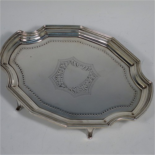 An Antique Victorian Scottish Sterling Silver teapot stand, having a shaped and cut-cornered oval body with an applied reeded border, the flat ground with a hand-engraved beaded band surrounding a central vacant cartouche, and all sitting on four flange feet. Made by Hamilton & Inches of Edinburgh in 1883. The dimensions of this fine hand-made antique silver teapot stand are length 18 cms (7 inches), width 13 cms (5 inches), and it weighs approx. 150g (4.8 troy ounces).