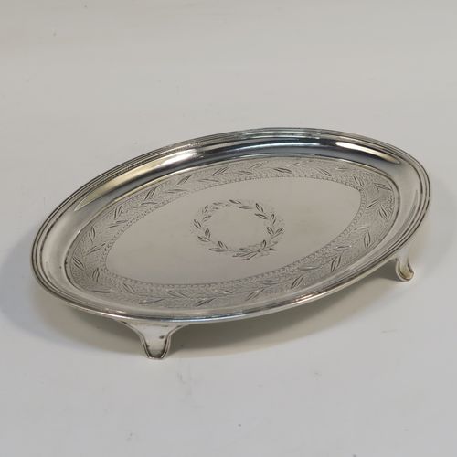 A very handsome Antique Georgian Sterling Silver teapot stand, having an oval body with a band of hand-engraved floral decoration, a central vacant laurel-leaf cartouche, a raised border with an applied reeded edge, and sitting on four flange  feet. This elegant antique silver teapot stand 
was made in London in 1796. The dimensions of this fine hand-made antique silver teapot stand are length 17 cms (6.75 inches), width 12 cms (4.75 inches), and it weighs approx. 127g (4 troy ounces).   